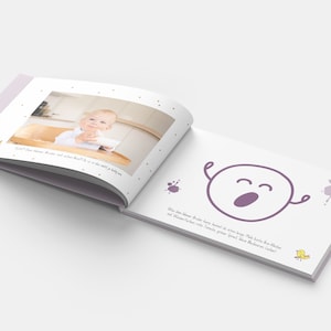Op de afbeelding: Een paars en wit babyfotoalbum met een foto van een baby op de linkerpagina en een paars cartoon gezicht met een grote geeuw op de rechterpagina. De tekst op de rechterpagina luidt "Was das kleine Baby heute lernen will, das lernt es heute. Mit ganz viel Freude und ganz viel Mut. Das kleine Baby lernt!"