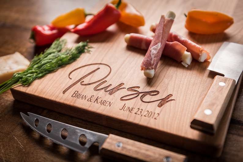 May include: Personalized wooden cutting board with the name "Purser" engraved in cursive, along with the names "Brian & Karen" and the date "June 23, 2012". The board has a built-in knife holder and a small knife.