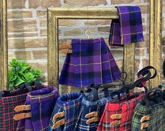May include: A collection of plaid skirts in various colors, including purple, red, green, and blue. Each skirt features a leather buckle detail and an elastic waistband. A matching scarf is also displayed.