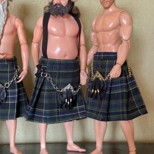 May include: Three male dolls with muscular builds wearing traditional-style kilts in a dark green, blue, and black plaid pattern. Each doll features a small sporran accessory attached with a gold or silver chain, and the central doll wears black suspenders.