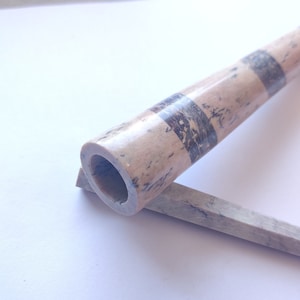 Op de afbeelding: Een houten pijp met een zwart-wit gestreept ontwerp. De pijp is gemaakt van natuurlijk hout en heeft een gladde afwerking.