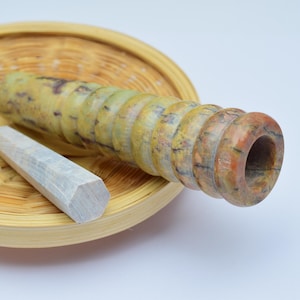 Può includere: Un mortaio e un pestello in legno. Il mortaio è in legno marrone chiaro con una finitura naturale. Il pestello è in legno grigio chiaro con una finitura liscia. Il mortaio e il pestello sono appoggiati su un cesto intrecciato.