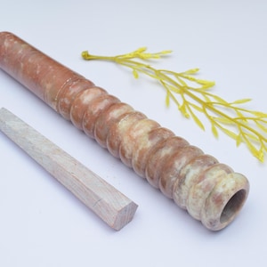 Könnte beinhalten: Eine braune und weiße Steinpfeife mit einem geschnitzten Design. Die Pfeife ist etwa 25 cm lang und hat an einem Ende eine runde Öffnung.