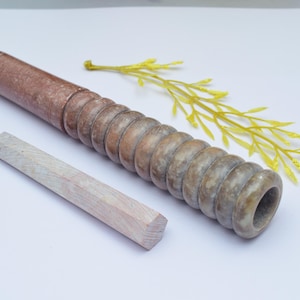 Könnte beinhalten: Eine braune und weiße Marmorpfeife mit einem Spiraldesign und einem weißen Holzreinigungswerkzeug.