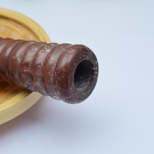 Op de afbeelding: Een close-up van een houten deegroller met een bruine en witte afwerking. De deegroller ligt op een houten oppervlak.