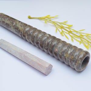 Può includere: Una pipa in pietra verde e marrone con un design a coste e un tampone in legno. La pipa è lunga circa 25 cm.