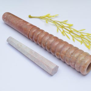 Könnte beinhalten: Eine braune und weiße Marmorpfeife mit einer runden Öffnung und einem kleineren, weißen Holzstift.