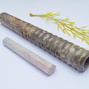 Può includere: Una pipa in marmo marrone e bianco con un design a coste e uno strumento di pulizia in legno.