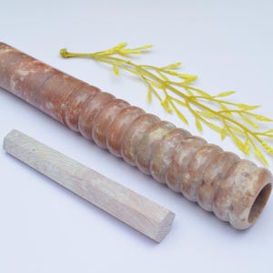 Könnte beinhalten: Ein brauner und weißer Marmor-Nudelholz mit einer geriffelten Oberfläche und einem weißen Holzstift.