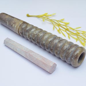 Könnte beinhalten: Eine braune und grüne Steinpfeife mit einem Spiralmuster und einem Holzstößel. Die Pfeife ist etwa 38 cm lang.
