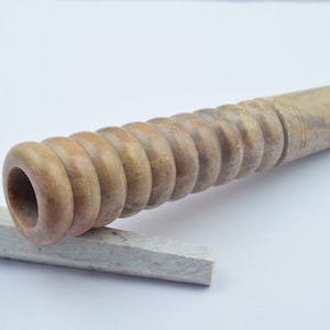 Op de afbeelding: Een bruine en beige stenen pijp met een spiraalvormig ontwerp. De pijp is gemaakt van een natuurlijk materiaal en heeft een gladde afwerking.