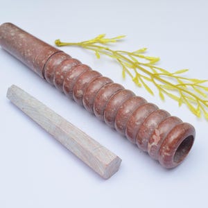 Op de afbeelding: Een bruine en witte marmeren deegroller met een getextureerd oppervlak en een bijpassende houten pen. De deegroller is ongeveer 30 cm lang.