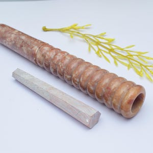 Op de afbeelding: Een bruine en witte marmeren deegroller met een getextureerd oppervlak en een witte houten pen.