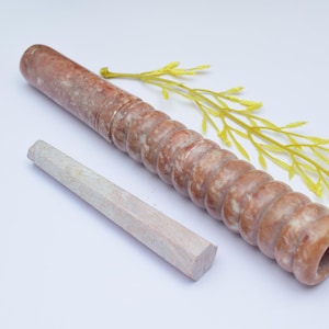 Op de afbeelding: Een bruine en witte marmeren deegroller met een getextureerd oppervlak en een witte houten pen.