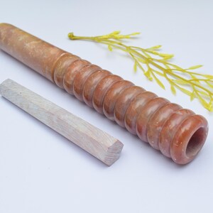 Könnte beinhalten: Eine braune und weiße Steinpfeife mit einem gerippten Design und einem weißen Holzstift.