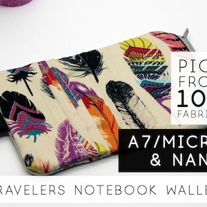 May include: A small, beige fabric wallet with a zipper closure and a colourful feather pattern. The wallet is labelled "A7/MICRO & NANO" and "TRAVELERS NOTEBOOK WALLET". The text "PICK FROM 100 FABRICS" is also visible.