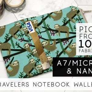 May include: A turquoise fabric wallet with a sloth pattern. The wallet has a zipper closure and a slot for a credit card. The text "PICK FROM 100 FABRICS" and "A7/MICRO & NANO" is printed on the image. The text "TRAVELERS NOTEBOOK WALLET" is printed at the bottom of the image.
