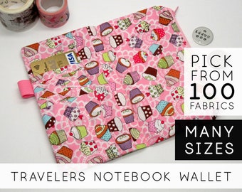 May include: Pink fabric wallet with a cupcake pattern. The wallet has a zipper closure and a pocket for cards. The text "TRAVELERS NOTEBOOK WALLET" is printed on the bottom of the image. The text "PICK FROM 100 FABRICS MANY SIZES" is printed on the right side of the image.