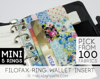 May include: A close-up of a mini 5-ring Filofax planner with a floral fabric wallet insert. The insert has a slot for cards and a white elastic band. The text "PICK FROM 100 FABRICS" is visible in the image.