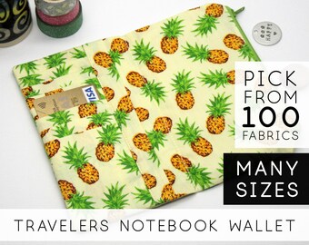 May include: A yellow and green fabric wallet with a pineapple pattern. The wallet has multiple card slots and a zipper closure. The text "PICK FROM 100 FABRICS" and "MANY SIZES" is visible in the image. The text "TRAVELERS NOTEBOOK WALLET" is also visible in the image.