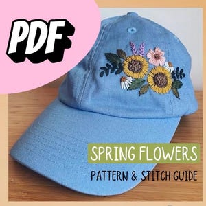 May include: Light blue baseball cap with embroidered sunflowers, daisies, and other spring flowers. The text "SPRING FLOWERS PATTERN & STITCH GUIDE" is displayed on the front of the cap. A pink circle with the word "PDF" is in the upper left corner.
