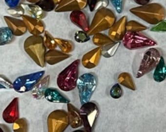 Puede incluir: Surtido de brillantes de cristal de forma de lágrima en varios tonos de azul, verde, rojo, dorado y morado.