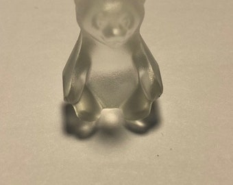 May include: A clear glass bear figurine. The bear is sitting upright with its paws in front of it.