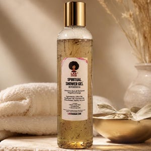 May include: A clear plastic bottle of Lab Shaman Spiritual Shower Gel with a gold cap. The liquid inside is translucent with visible dark herbal particles. The label features a graphic of a person with an afro and text including ingredients.