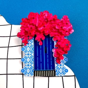May include: A blue door with a white and blue tiled frame, covered in a pink floral garland. The door has a black and white striped trim.