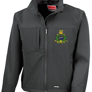 May include: A dark grey softshell jacket with a full zip and a high collar. The jacket has a small chest pocket and a colourful embroidered emblem on the left breast. The brand name "Result" is visible on the collar.