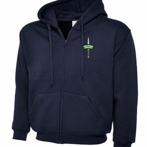 May include: Navy blue zip-up hoodie with a hood and front pockets. It has a small green and white embroidered patch on the chest that reads "ROYAL MARINES COMMANDO". The hoodie has drawstrings and ribbed cuffs.