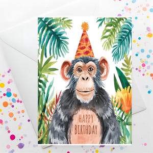 Könnte beinhalten: Geburtstagskarte mit einer Aquarellillustration eines Schimpansen mit Partyhut. Der Schimpanse ist von tropischen Pflanzen umgeben, mit den Worten "HAPPY BIRTHDAY" auf seiner Brust. Die Karte befindet sich in einem weißen Umschlag.