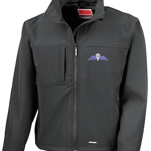 May include: Black softshell jacket with a full zip, stand-up collar, and a chest pocket. It has a purple and white parachute logo on the chest. The jacket has the brand name "Result" on the label.