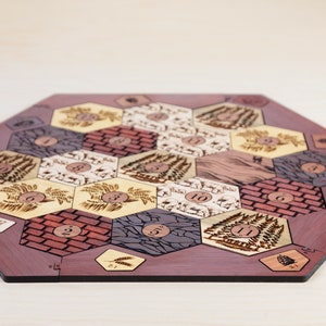 Puede incluir: Un tablero de juego hexagonal de madera con un borde rojo-marr&oacute;n. El tablero est&aacute; dividido en fichas hexagonales con diferentes dise&ntilde;os, incluyendo campos de trigo, ladrillo, madera, ovejas y piedra. Cada ficha tiene un n&uacute;mero impreso.