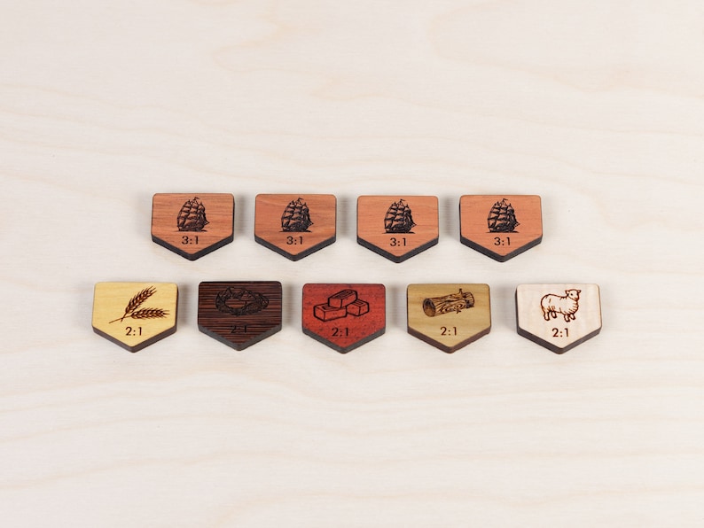 Puede incluir: Ocho fichas de juego de madera con diferentes im&aacute;genes y el texto "2:1" o "3:1" impreso en ellas. Las im&aacute;genes incluyen trigo, un tronco, una oveja y una pila de ladrillos.