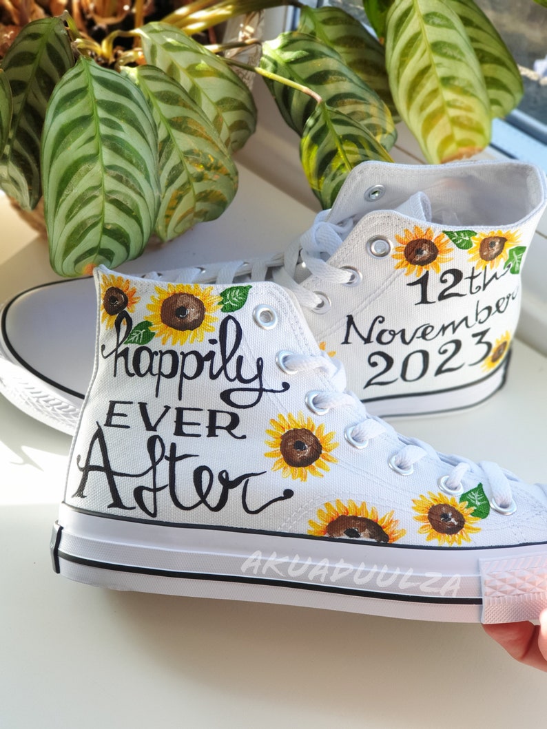 May include: White canvas high-top sneakers with a sunflower design and the text "happily ever after" on one shoe and "12th November 2023" on the other.