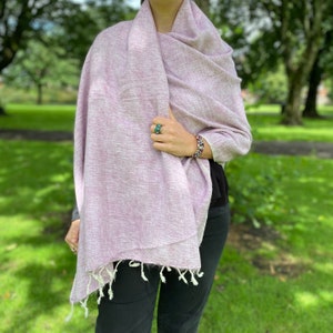 May include: A soft, light purple shawl with white fringe. The shawl is made of a lightweight fabric and is perfect for layering.