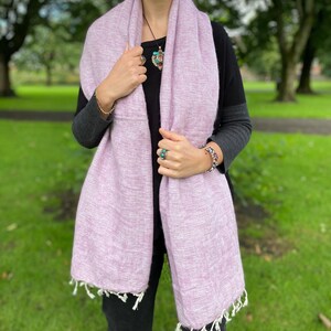 May include: A soft, light purple scarf with fringe edges. The scarf is made of a lightweight fabric and is perfect for layering.