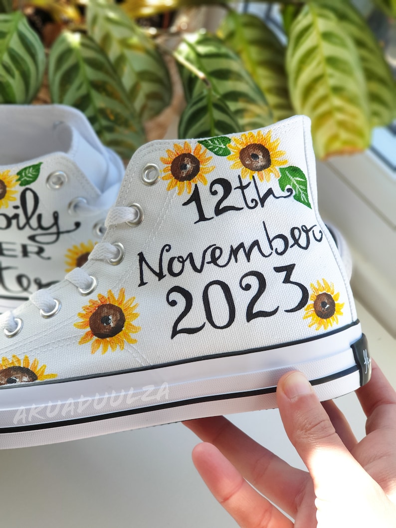 May include: White canvas high-top sneakers with a hand-painted design featuring sunflowers and the text "12th November 2023".