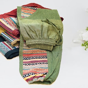 May include: Green, red, and blue patterned pants with a drawstring waist. The pants are folded and stacked on top of each other.