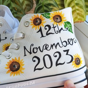 May include: White canvas high-top sneakers with hand-painted sunflowers and the text "12th November 2023".