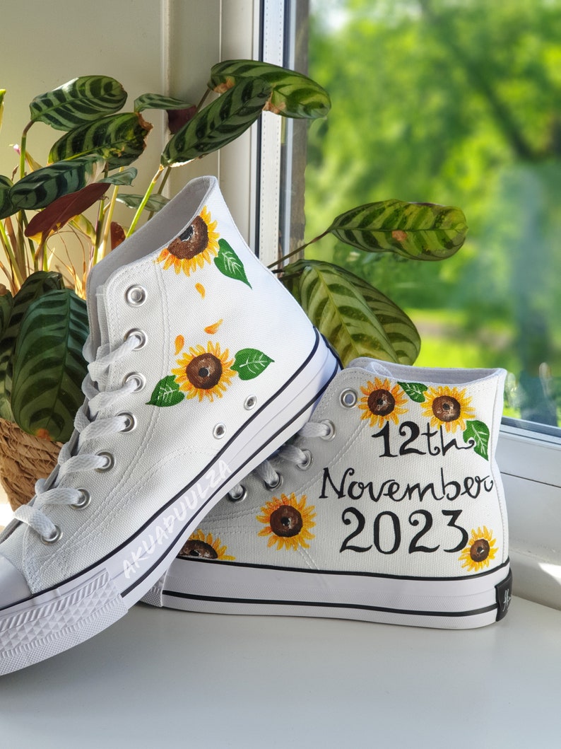 May include: White high-top canvas shoes with hand-painted sunflowers and the text "12th November 2023".