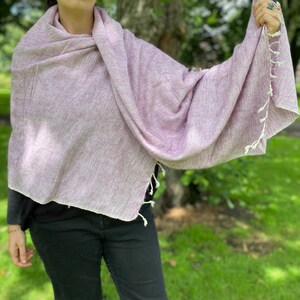 May include: A soft, light purple shawl with white fringe. The shawl is made of a lightweight fabric and is perfect for layering.