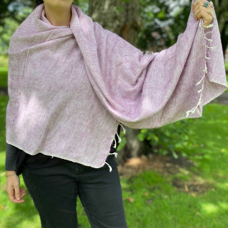 May include: A soft, light purple shawl with white fringe. The shawl is made of a lightweight fabric and is perfect for layering.