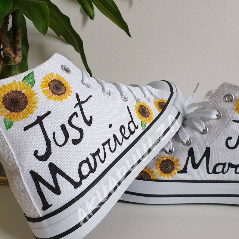 May include: White high-top canvas shoes with black writing that says "Just Married" and painted sunflowers.