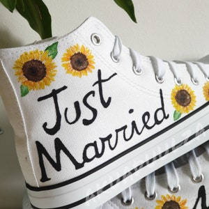 May include: White high-top canvas shoes with black painted text "Just Married" and sunflower designs.