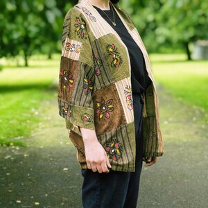 Peut inclure: Veste kimono patchwork aux tons verts, marron et beige. La veste pr&eacute;sente une vari&eacute;t&eacute; de carr&eacute;s &agrave; motifs floraux et ray&eacute;s. L'avant ouvert et la coupe ample cr&eacute;ent une esth&eacute;tique boh&egrave;me d&eacute;contract&eacute;e.