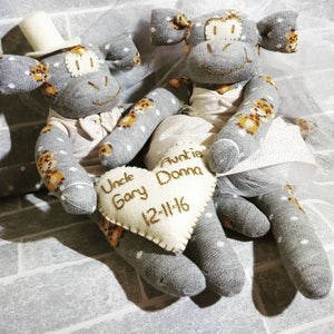 May include: Two grey sock monkey wedding figurines with white polka dots and brown tiger stripes. The bride is wearing a white tulle veil and the groom has a white top hat. They are holding a heart-shaped pillow with the text "Uncle Gary Auntie Donna 12-11-16".