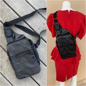 May include: Black leather crossbody bag with multiple zippered compartments and a black adjustable strap. The bag is shown on a wooden surface and on a red dress form.