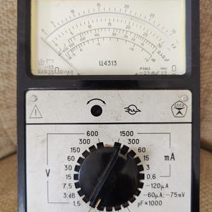 Puede incluir: Multímetro analógico vintage en blanco y negro con dial y múltiples configuraciones. El medidor tiene un indicador de aguja, un dial giratorio y varios terminales de entrada. La cara del medidor tiene el texto "Ц4313" y "CCCP".